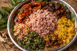 スリランカ料理ライス＆カリーの俯瞰写真。中央の白米を囲むように、赤い魚カレー、ダーク・ローストの濃褐色カレー、黄色いダル、グリーンのマッルン、ココナッツサンボルが並ぶ。脇にカレーリーフと乾燥させたモルディブフィッシュ。