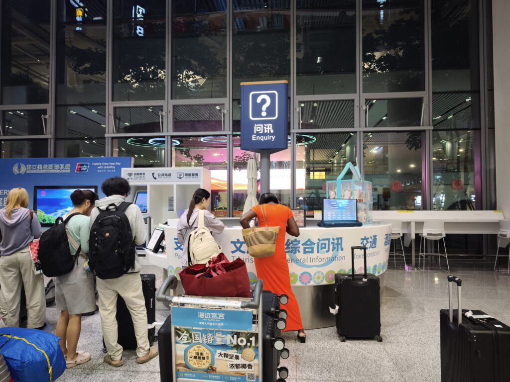 海口美蘭空港のEnquiry（問訊）カウンター。トランジット特典を申請する旅客が並ぶ」]